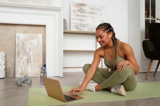 An individual is participating in a virtual fitness class on a laptop in their living room. They are following the instructions of a fitness instructor who is visible on the screen. The living room is tidy and well-lit.