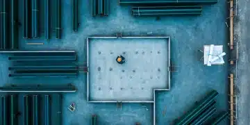 Aerial view of a construction site with a worker on a concrete foundation, surrounded by green steel beams, symbolizing strategic brand building.